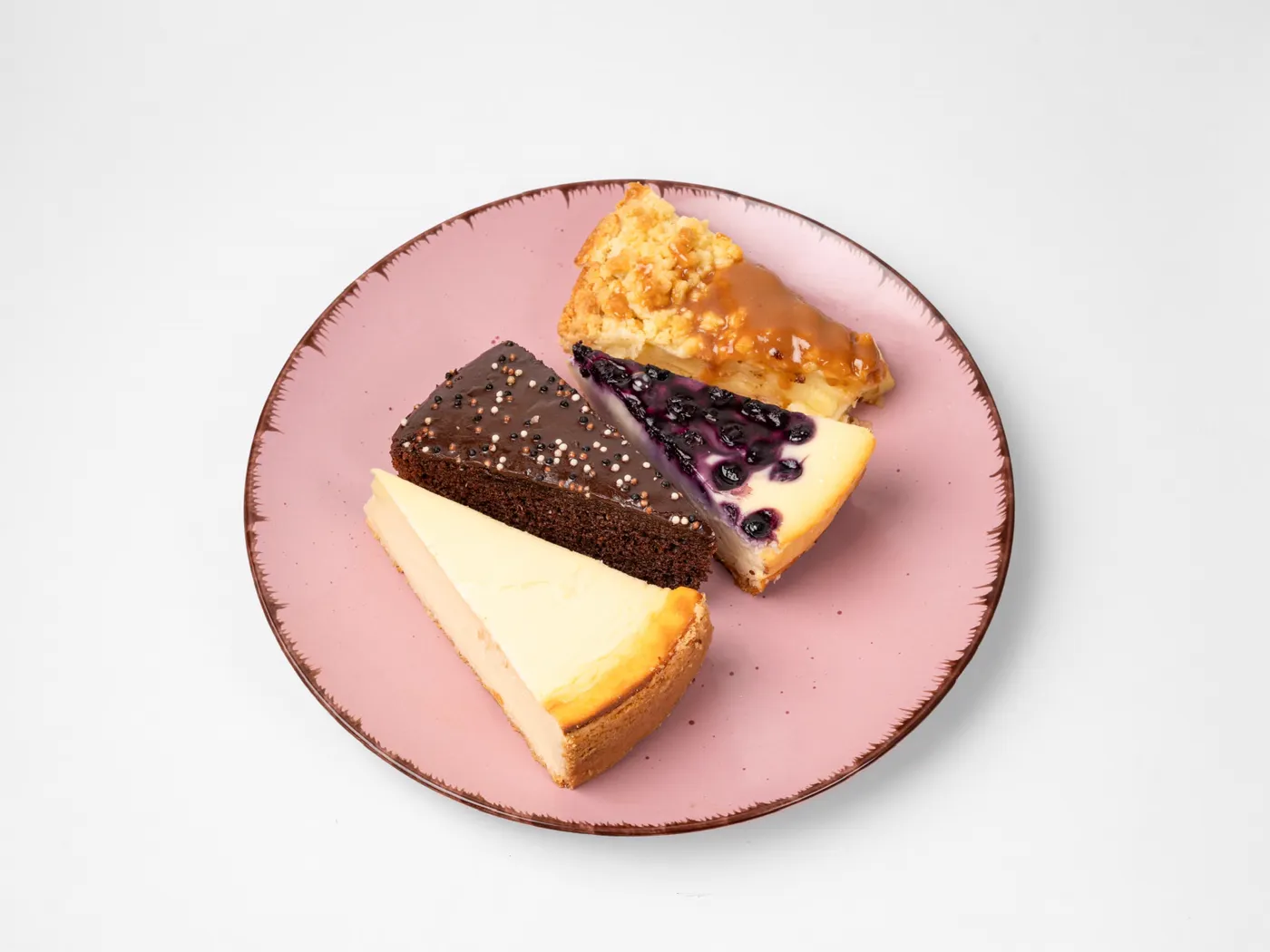 Teller mit verschiedenen Kuchenstücken: Käsekuchen, Blaubeer-Käsekuchen, Schokoladenkuchen und Apfelkuchen